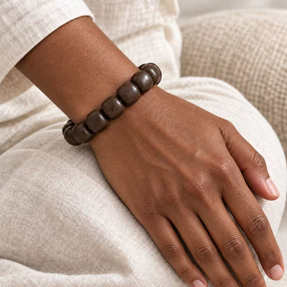 Dark brown wood bead bracelet worn on a wrist against a light fabric outfit.